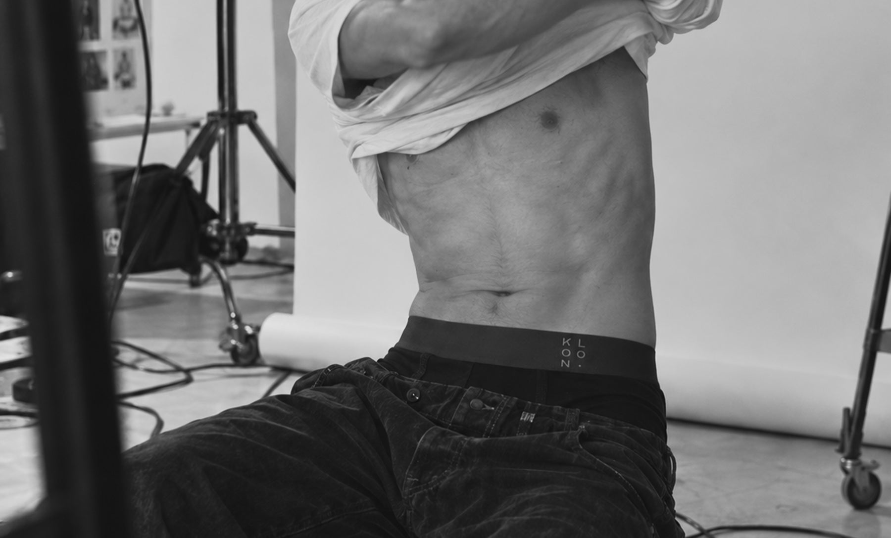 Behind the scenes, lifting shirt to show the KLOON waistband on set